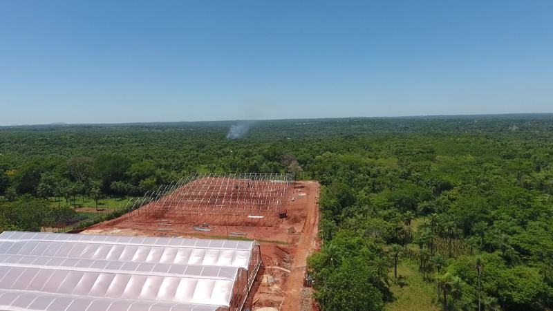 Estructuras de invernadero en montaje sobre terreno explanado, vista de dron